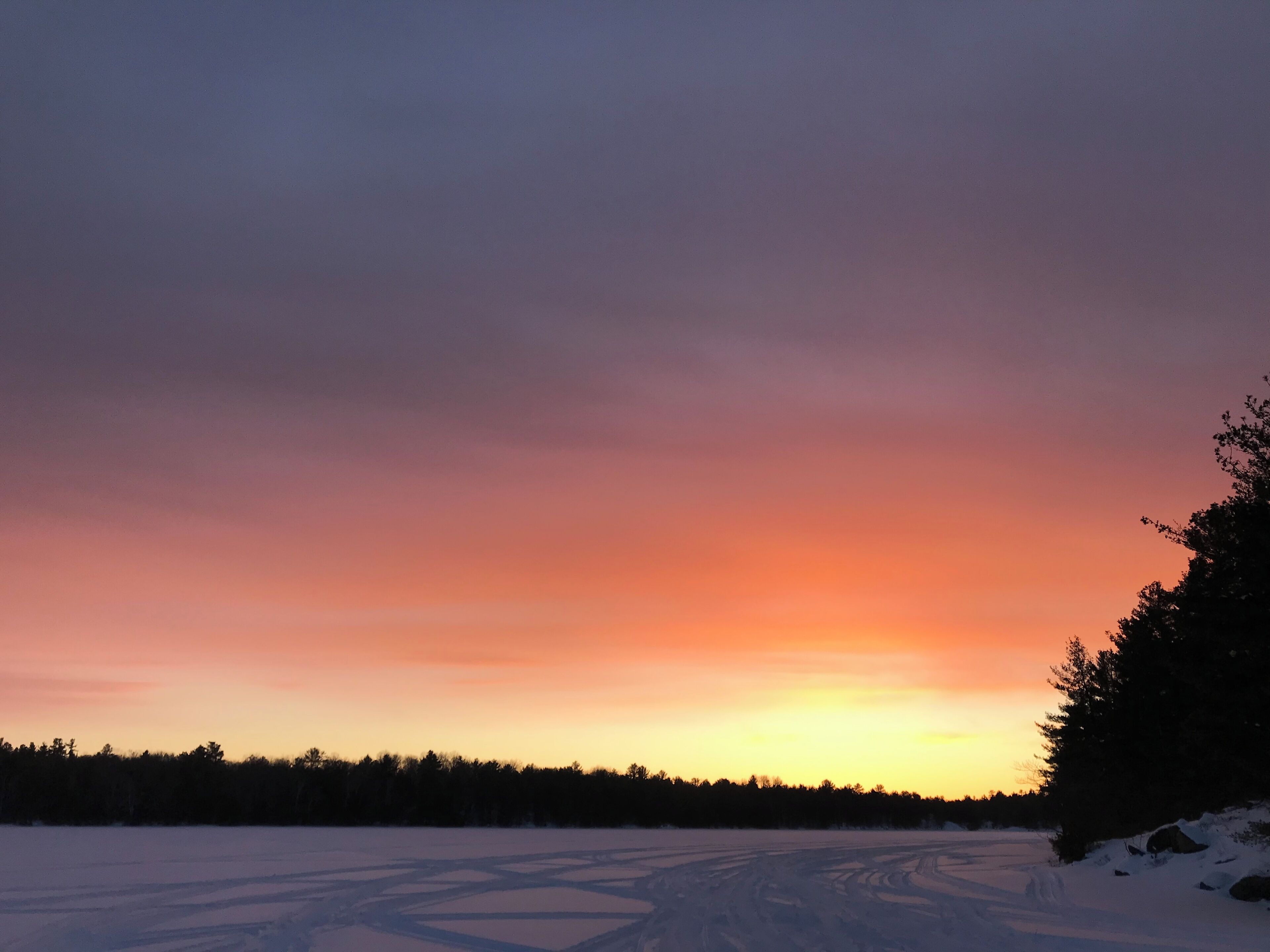 A snowy landscape with a clear sky during sunset.