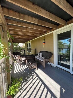 Relax in a serene outdoor space with a pergola overhead, wicker chairs, and a sofa perfect for dining or unwinding.