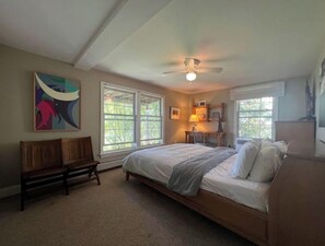 Relax in this serene bedroom with a large bed, ceiling fan, and comfortable bench.
