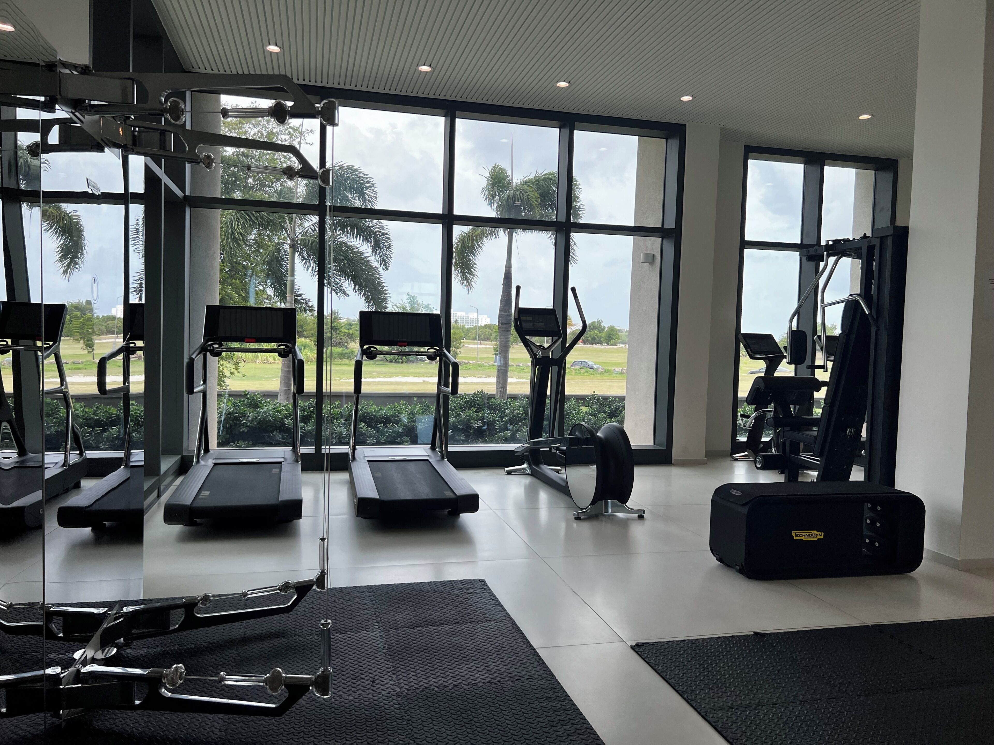 Et fitnessrum med løbebånd, en motionscykel og et styrkeapparat.
