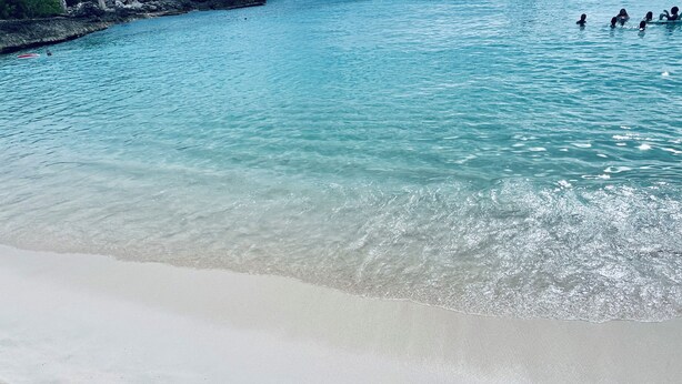Una playa con agua turquesa cristalina y arena blanca.