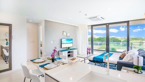 Una habitación de hotel moderna con un balcón grande, un comedor, una cama y un televisor.