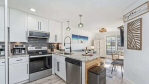 Una cocina moderna con armarios blancos, electrodomésticos de acero inoxidable y una isla central.