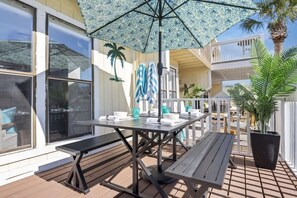 Un patio al aire libre con una mesa, bancos, un paraguas estampado y una planta en maceta.