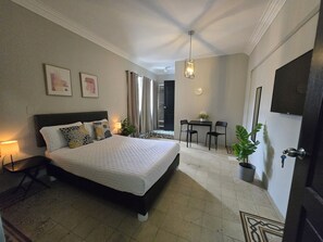 A bedroom with a bed, bedside table, lamp, and a small table with chairs. - Singular Centro Histórico (Mexico City)