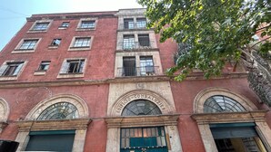 A red brick building with arched windows and a green door, labeled "EDIFICIO-COMBALUZIER".