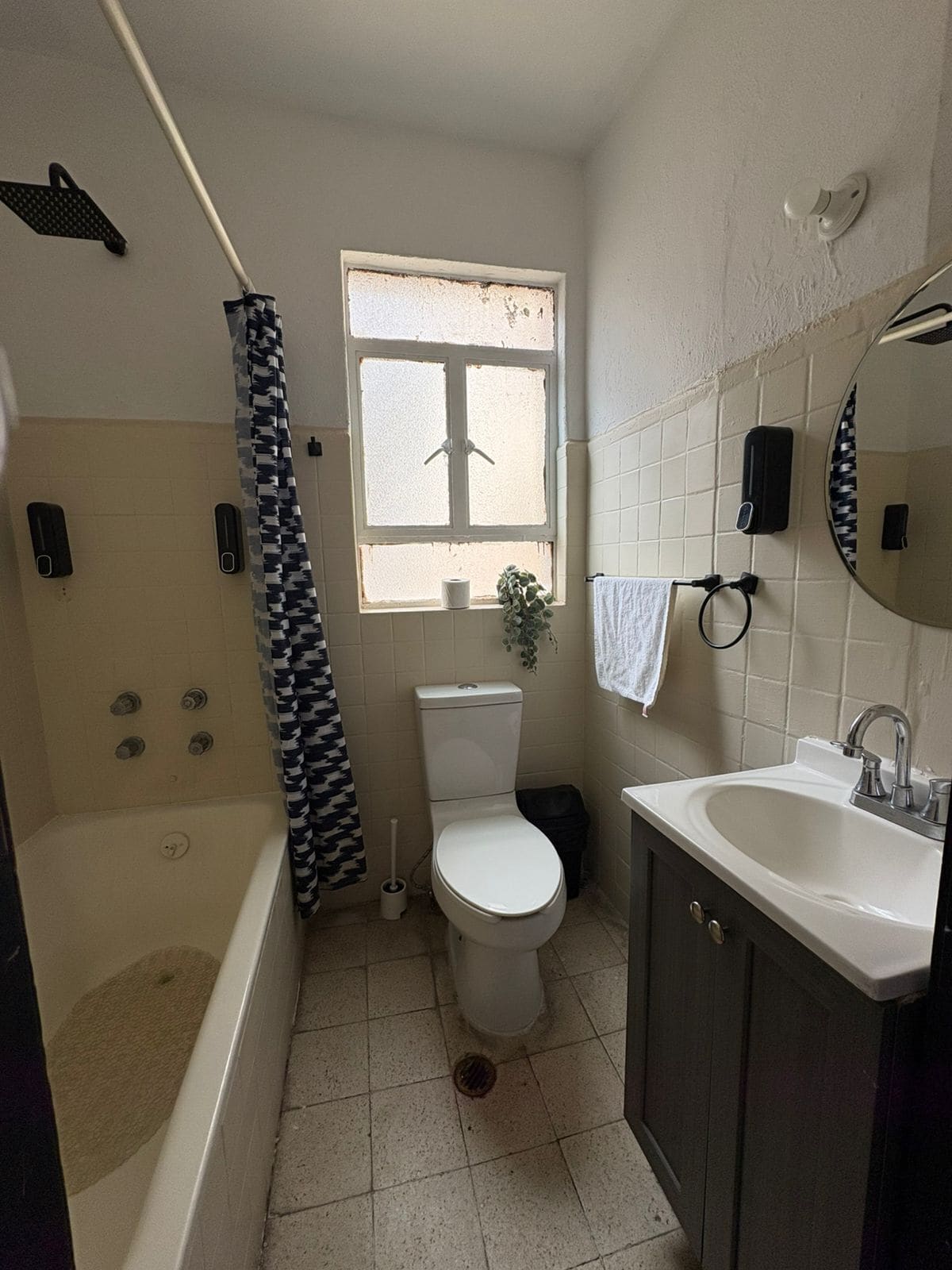 A bathroom with a bathtub, toilet, sink, and a window with a view.