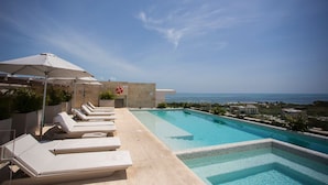 A rooftop pool with lounge chairs and umbrellas, overlooking a coastal view. - Business studio-apartment near the beach (Cancún)