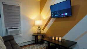 A living room with a sofa, a table with candles, a TV, and a lamp. - "Serene Escape: Leave Worries Behind"
 (Wilkes-Barre)