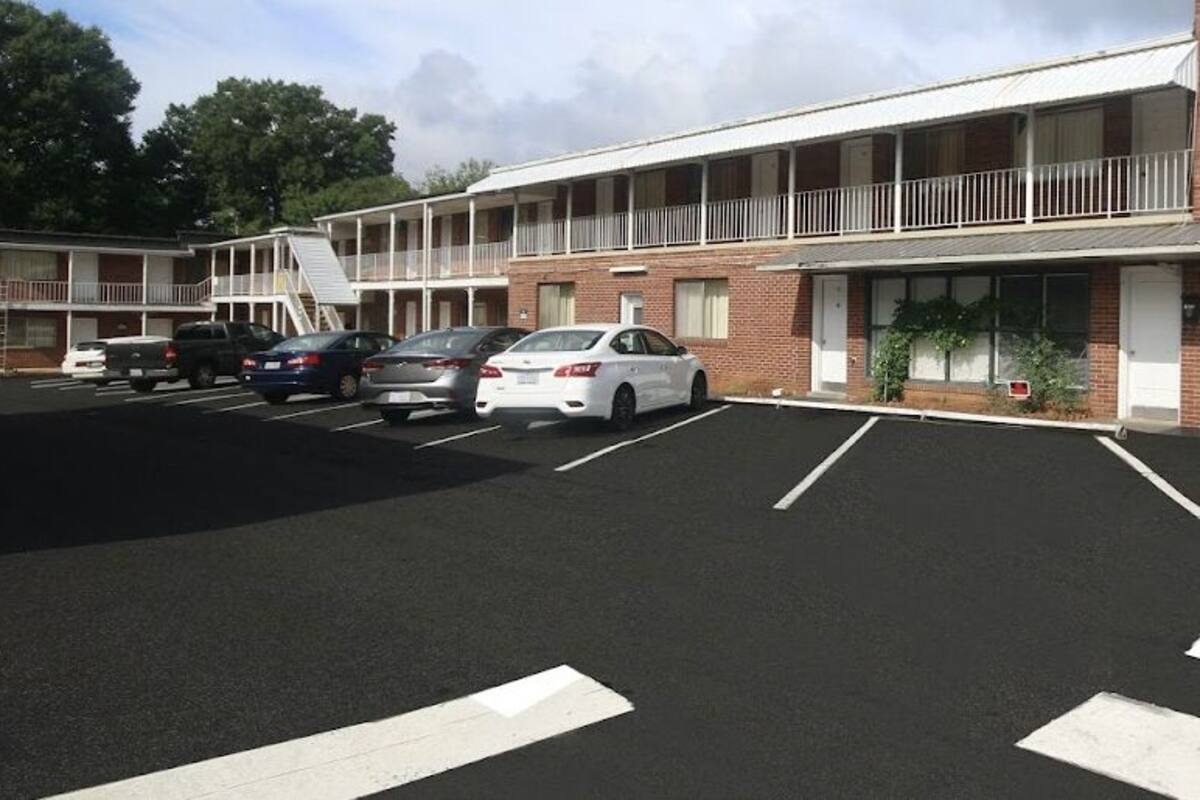 A motel with a two-story structure, a parking lot with several cars, and a sign that reads "BEST IN-TOWN MOTEL".