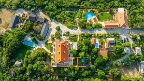 Een luchtbeeld van een resort met meerdere gebouwen, een zwembad en weelderige begroeiing.