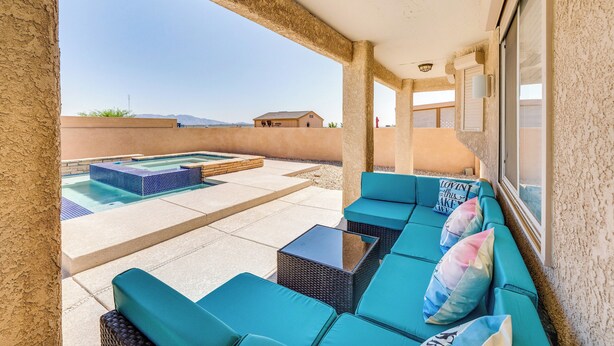 A covered outdoor area with a pool, seating, and a view of distant buildings.