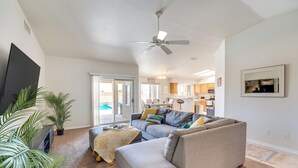 A modern living room with a grey sectional sofa, a flat-screen TV, and a ceiling fan.