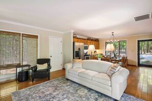 Relax in this open-plan living space featuring a sofa, dining area, and kitchen, perfect for meal preparation and relaxation.
