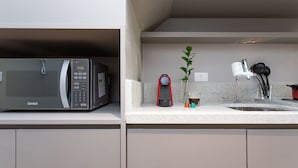A kitchen with a microwave, a red coffee maker, a plant, and a sink. - Next Haddock by Viva - Apartamentos próximos ao MASP e a metros da Estação Consolação e Avenida Paulista (São Paulo)