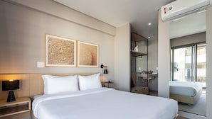 A hotel room with a large bed, a bedside table with a lamp, a wall-mounted air conditioner, and a bathroom visible through an open door. - Next Haddock by Viva - Apartamentos próximos ao MASP e a metros da Estação Consolação e Avenida Paulista (São Paulo)