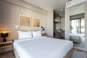 A hotel room with a large bed, a bedside table with a lamp, a wall-mounted air conditioner, and a bathroom visible through an open door. - Next Haddock by Viva - Apartamentos próximos ao MASP e a metros da Estação Consolação e Avenida Paulista (São Paulo)
