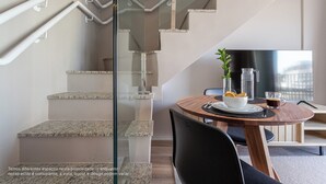 Un interior moderno con una escalera, un comedor con mesa y sillas, y un televisor.
