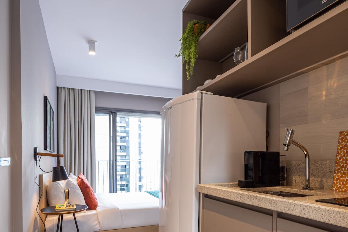 Eine moderne Küche mit integriertem Kühlschrank, Spüle und Arbeitsplatte. Ein Fenster bietet Blick auf Gebäude.
