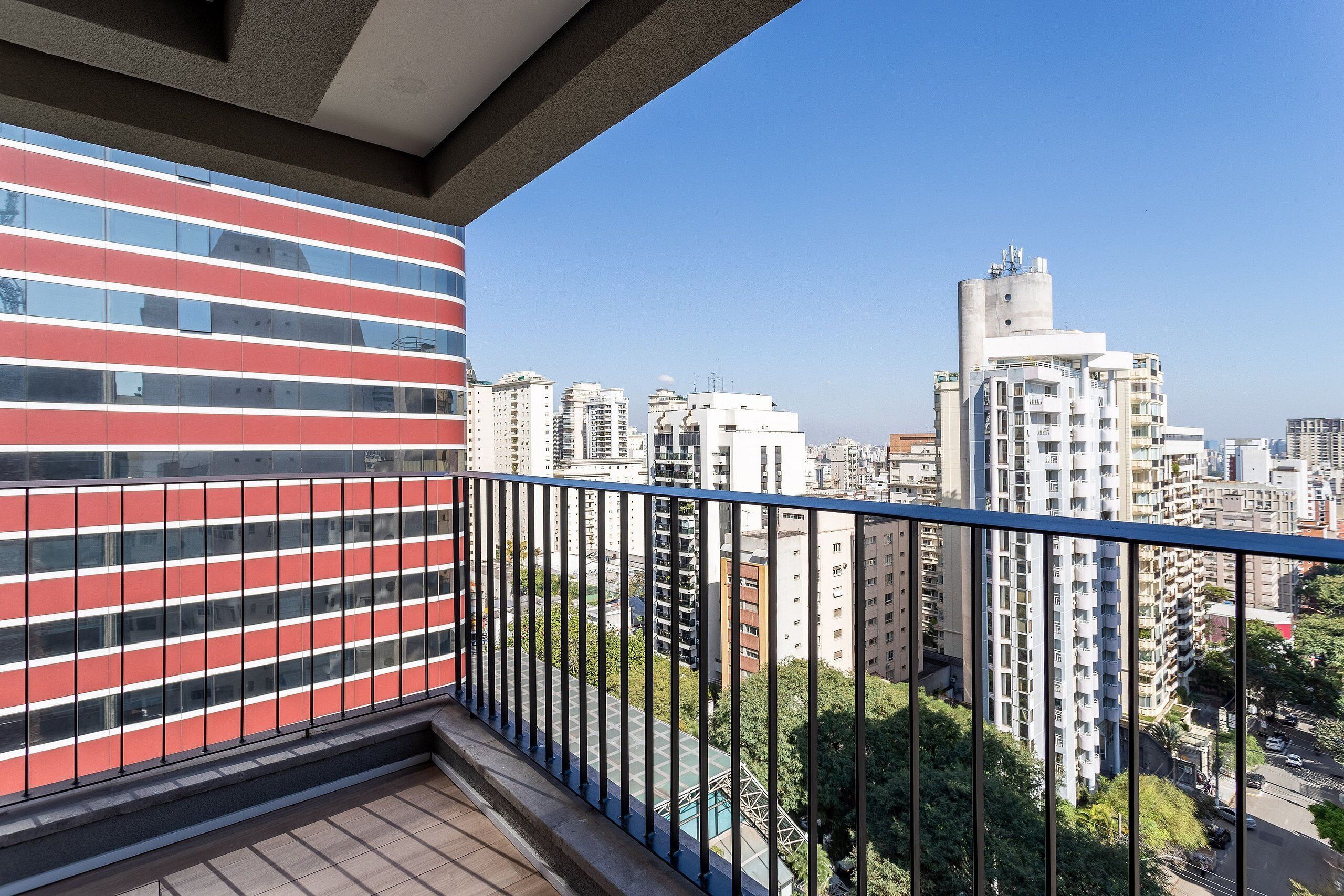 Een balkon met uitzicht op een stadsbeeld, inclusief hoge gebouwen en een heldere lucht.
