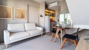 Una sala de estar moderna con un sofá blanco, una mesa de comedor con sillas y obras de arte en la pared.