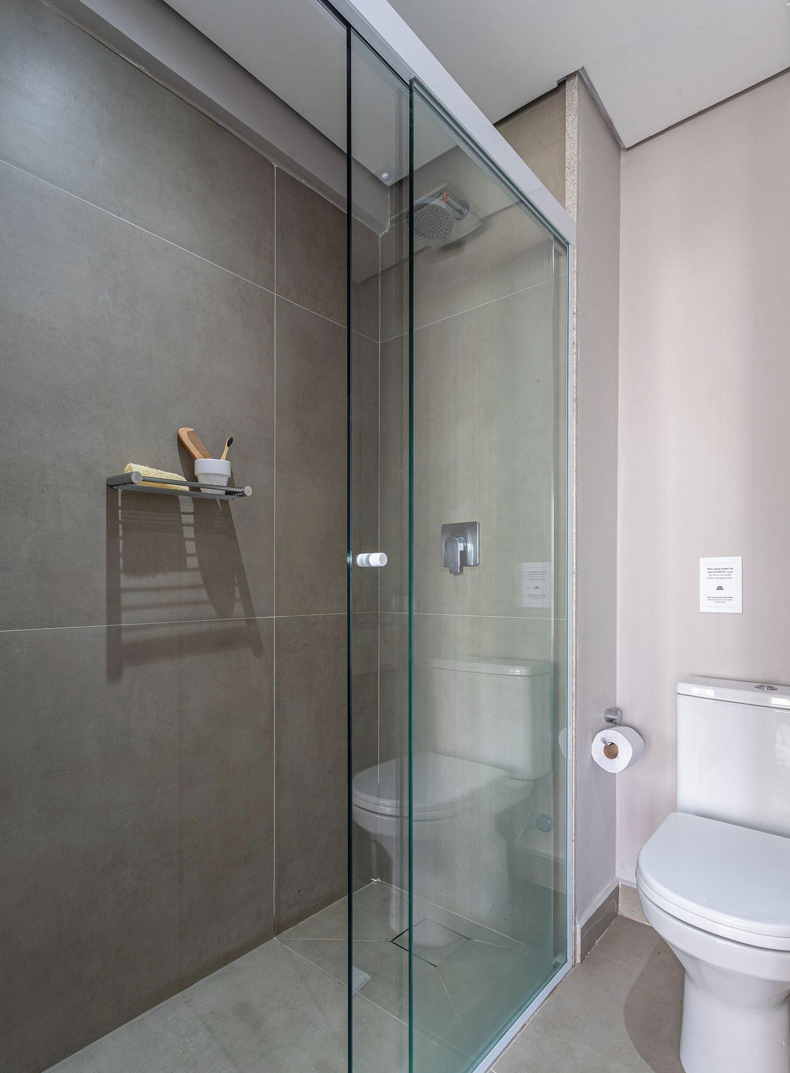 Ein modernes Badezimmer mit einer Glaskabine zur Dusche, einer Toilette und Ablage für Toilettenartikel.