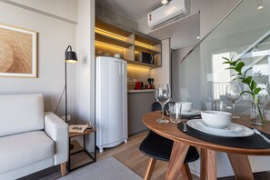A compact living space with a kitchenette, a dining area, and a seating area with a sofa and a table set for dining. - Next Haddock by Viva - Apartamentos próximos ao MASP e a metros da Estação Consolação e Avenida Paulista (São Paulo)