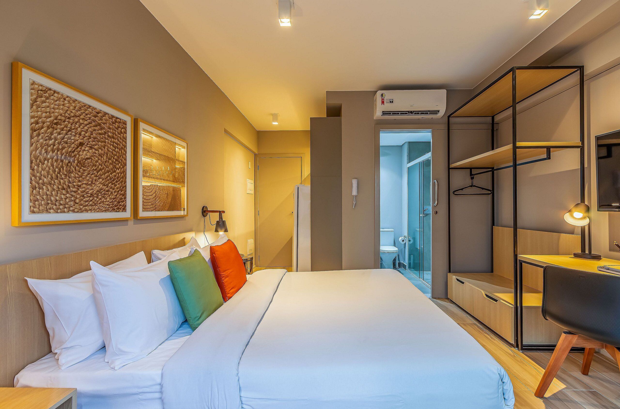 A hotel room with a bed, a desk, and a wardrobe.