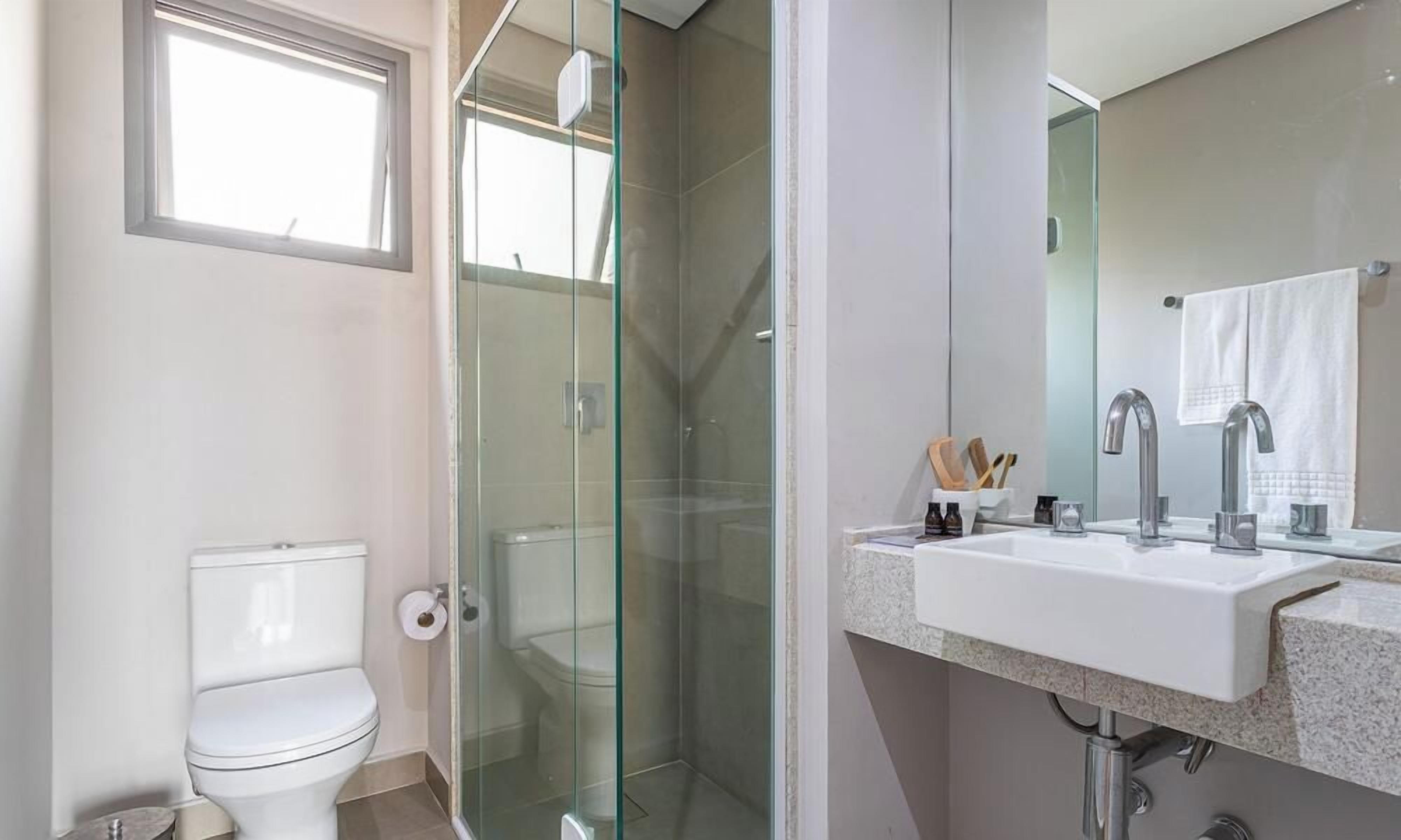 Een badkamer met een douchecabine van glas, een wit toilet en een wastafel met spiegel.