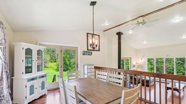 A dining area with a wooden table and chairs, a white cabinet with glass doors, and a view of the outdoors. - Charming & Scenic Gouldsboro Getaway w/ Patio! (Gouldsboro)