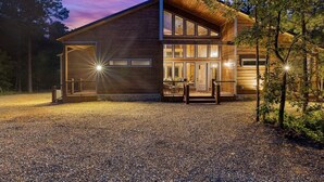 Une maison moderne à deux étages, dotée d’un grand garage ouvert et d’un porche abrité.