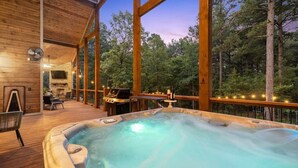 Un bain à remous sur une terrasse en bois, avec vue sur une forêt.