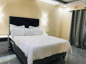 Ein ordentlich bezogenes Bett mit weißen Leinen und einem schwarzen Kopfteil in einem Hotelzimmer.