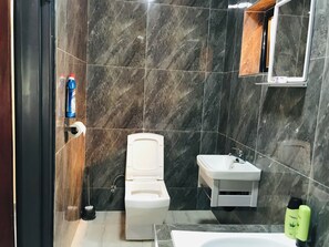 Ein Badezimmer mit Toilette, Waschbecken und Duschbereich.