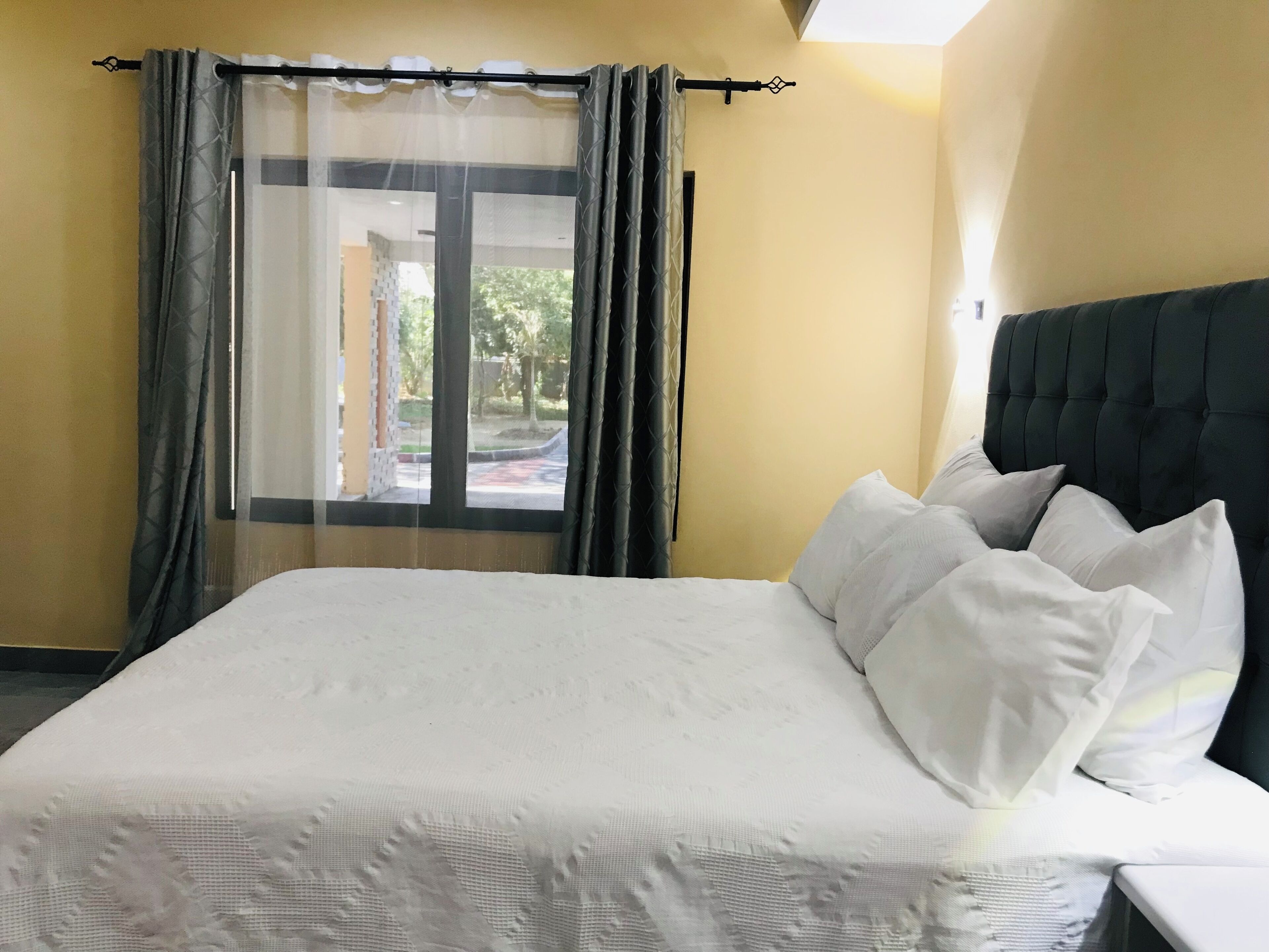 A hotel room with a large bed, a headboard, and a window with curtains.