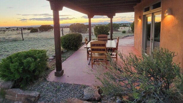 An outdoor patio with a table and chairs, a covered area with a roof, and a view of the landscape. - Vista Gloriosa - panoramic mountain views in Eldorado. (Santa Fe)