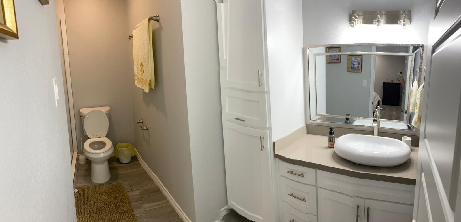 A bathroom with a toilet, sink, and mirror.