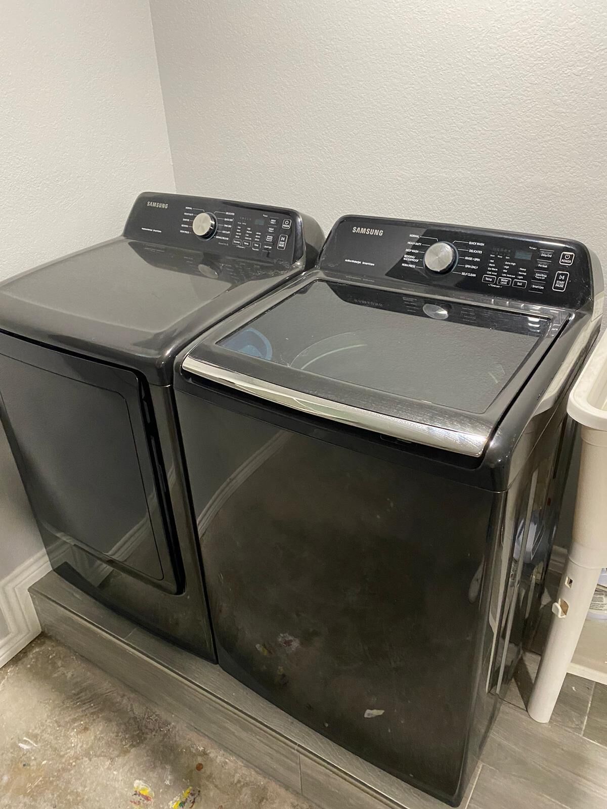 Et frontbillede af en sort Samsung vaskemaskine og tørretumbler i ét, med betjeningspaneler øverst.
