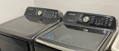 Et frontbillede af en sort Samsung vaskemaskine og tørretumbler i ét, med betjeningspaneler øverst.