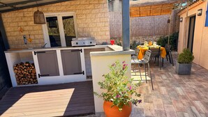 Eine Außenpatio mit Grill, Sitzgelegenheit und Kübelpflanzen.