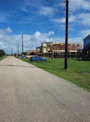 Rural village nestled along a winding unpaved road, surrounded by grassy areas and utility poles.