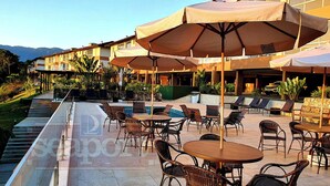 Une terrasse d’hôtel avec des sièges en plein air, une piscine et une vue sur les montagnes.