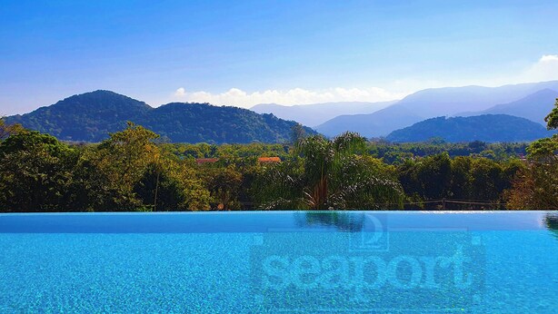Une magnifique piscine à débordement d’un bleu profond, offrant une vue sur les montagnes et une végétation luxuriante.
