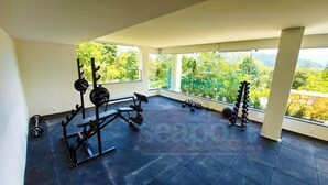 Une salle de sport équipée de matériel d’exercice et dotée de grandes fenêtres donnant sur un paysage magnifique.