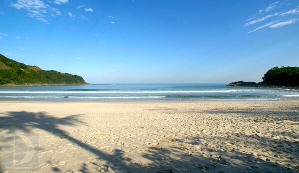 A beach with a clear sky, calm sea, and sandy shore.