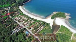 Vue aérienne d’une zone côtière comprenant une plage, une zone résidentielle et une zone clairement délimitée réservée aux copropriétés.