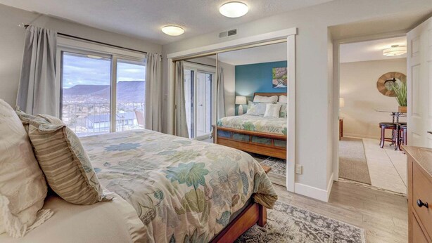 Un dormitorio con una cama grande, vistas de la ciudad y un balcón.