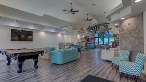 Una sala de estar moderna con mesa de billar, un sofá color turquesa y un mostrador de recepción.