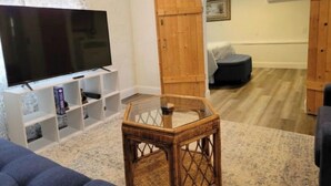 Una sala de estar con televisión de pantalla plana, muebles de madera y una alfombra estampada.