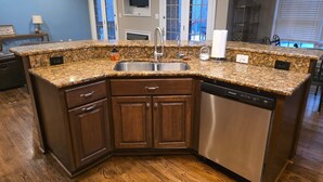 A kitchen with granite countertops, wooden cabinets, a stainless steel sink, and a dishwasher. - Large Private Home Near Charlotte Sleeps 15  Workspaces and Land - NO PETS (Dallas)